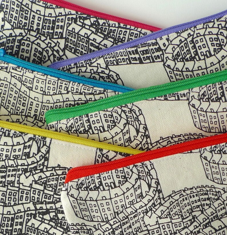 May include: Five zippered pouches with a black and white print of a city skyline. The pouches are lined with different colored zippers: red, purple, blue, green, and yellow.