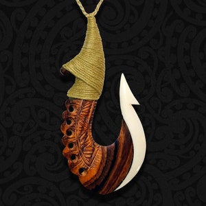 Puede incluir: Un collar de gancho de pesca de madera y hueso con tallas intrincadas y un cordón marrón y beige.