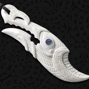 May include: A white bone carving of a bird with intricate details and a blue and green abalone shell inlay for the eye.