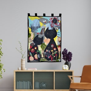 Pode incluir: Uma tape&ccedil;aria decorativa de parede com duas silhuetas de gatos pretos com desenhos florais e abstratos. A obra de arte tem um fundo colorido com uma variedade de formas e cores, incluindo amarelo, azul e vermelho. A tape&ccedil;aria &eacute; emoldurada com uma borda preta.