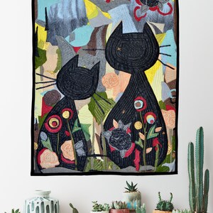 Pode incluir: Uma tape&ccedil;aria de parede com duas silhuetas de gatos pretos com motivos florais. A obra de arte apresenta um fundo texturizado e colorido com flores e folhagem. &Eacute; emoldurada com uma borda preta e tem la&ccedil;os pretos para pendurar, adequada para decora&ccedil;&atilde;o de casa.