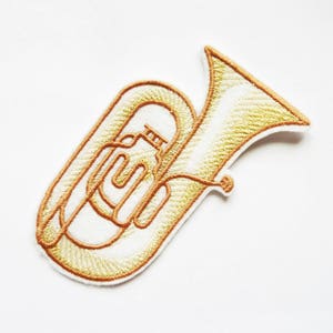 May include: A gold embroidered patch of a tuba, a brass musical instrument.