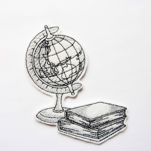 Pode incluir: Desenho bordado em preto e branco de um globo e uma pilha de livros. O globo está em um suporte e os livros estão empilhados um em cima do outro.