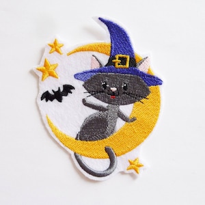 Peut inclure: Écusson brodé représentant un chat noir portant un chapeau de sorcière bleu, perché sur un croissant de lune jaune. Comprend des étoiles jaunes et une chauve-souris noire. Le patch a une bordure blanche.