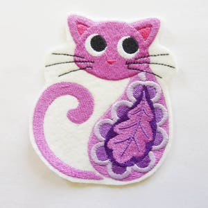 Peut inclure: Écusson brodé en forme de chat aux tons roses et violets, avec des moustaches noires et de grands yeux noirs. Le chat a un corps blanc et un motif de feuille décorative sur le côté. Pour vêtements ou accessoires.
