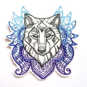 Op de afbeelding: Geborduurde strijkpatch met een gedetailleerd wolfskopontwerp met geometrische lijnen en een mandala-achtig patroon in tinten blauw en paars.