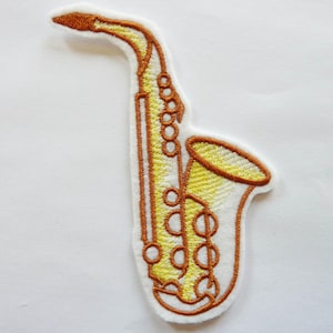 May include: Embroidered patch of a saxophone in shades of yellow and brown, outlined in brown. The patch has a white border. The saxophone design features detailed stitching, including the keys and bell of the instrument. Ideal for music lovers and musicians.