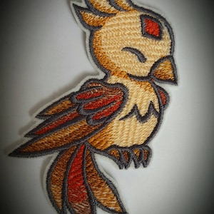 Op de afbeelding: Geborduurde strijkpatch van een cartoonvogel met bruine, oranje en rode veren. De vogel heeft een gesloten oog en een klein rood oog.