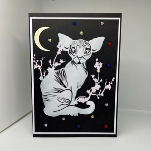 Sphynx à la coupe complexe assis au clair de lune avec des pierres précieuses colorées en forme de cœur montées sur du carton noir. Merci. Anniversaire. Toute occasion