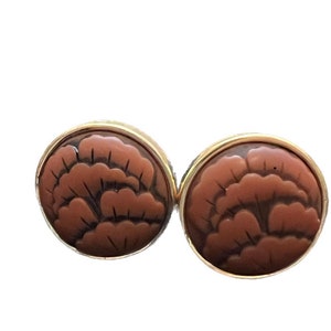 May include: A pair of brown and gold earrings with a carved floral design.