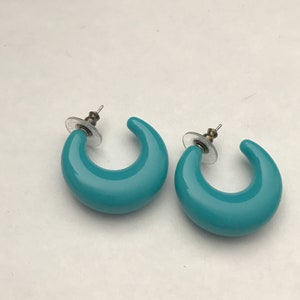 May include: A pair of turquoise blue hoop earrings with a smooth, rounded finish. The earrings have a simple, classic design and are perfect for everyday wear.