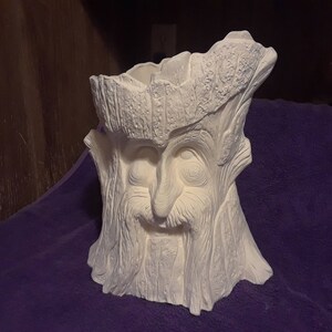 Peut inclure: Pot en céramique blanche en forme de souche d'arbre avec un visage. Le visage a une barbe, une moustache et des yeux.