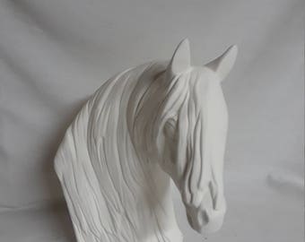 May include: White ceramic horse head sculpture with a detailed mane and flowing hair. The horse's head is tilted down, and the sculpture is unpainted.