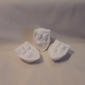 May include: Three white ceramic ornaments shaped like a boat with a sleeping mouse inside. The ornaments are blank and ready to be painted.