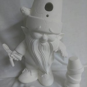 May include: White ceramic gnome figurine with a bird on its hat, holding a small rake in one hand. The gnome is wearing a hat with a hole in the top. The gnome is standing on a white surface. There is a separate white ceramic bird and a stack of three white ceramic pots.