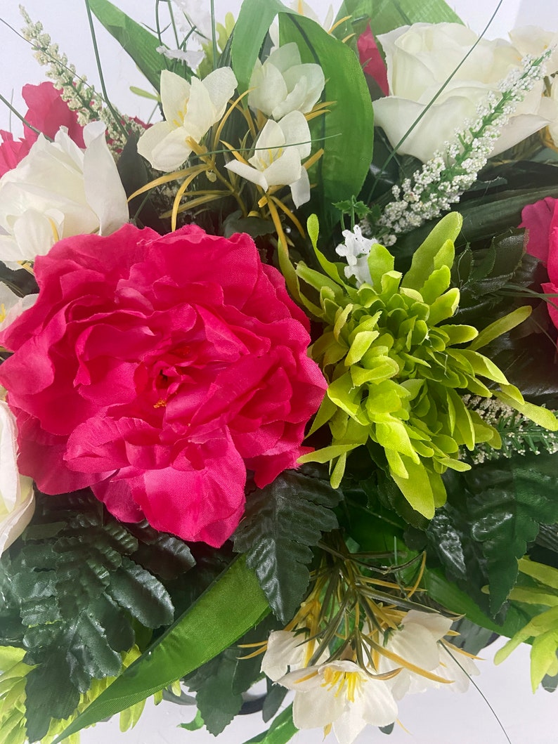 May include: A bouquet of artificial flowers in shades of pink, white, and green. The bouquet features a large pink peony, white roses, and green chrysanthemums.
