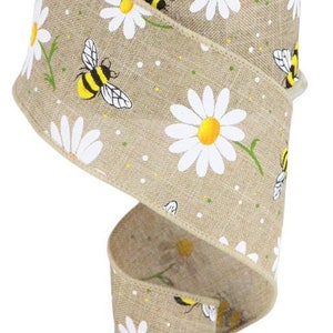 Op de afbeelding: Een rol bruin jute lint met een patroon van witte madeliefjes en gele bijen. Het lint is 2,5 inch breed.