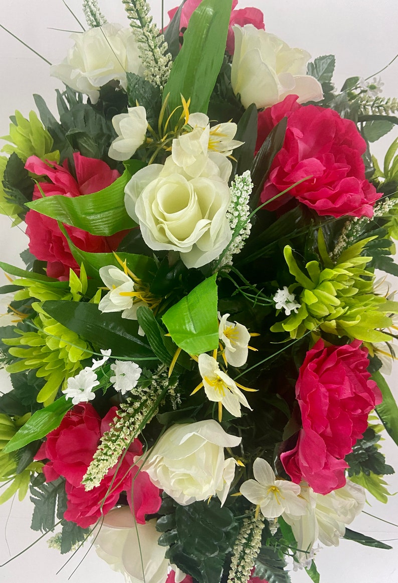 May include: A bouquet of artificial flowers with white roses, pink peonies, and green foliage.