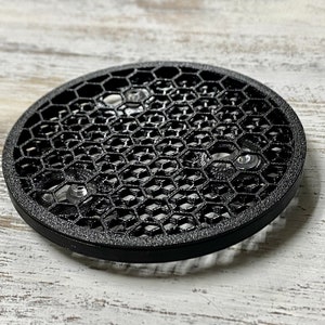 May include: Black round speaker grille with a honeycomb pattern and three silver screws.