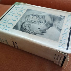 May include: A vintage hardback book titled "The Road to Glory" by F. Britten Austin. The book cover features a black and white illustration of a man in military uniform.