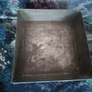 May include: A square metal baking pan with a silver finish. The pan has a slightly worn surface.