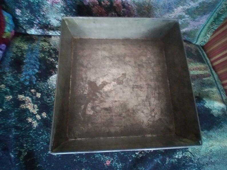 May include: A square metal baking pan with a silver finish. The pan has a slightly worn surface.