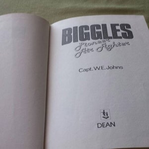 May include: An open book with the title "Biggles Pioneer Fire Fighter" in large, stylized text. The author's name, Capt. W.E. Johns, is below the title. The book's cover is not visible.