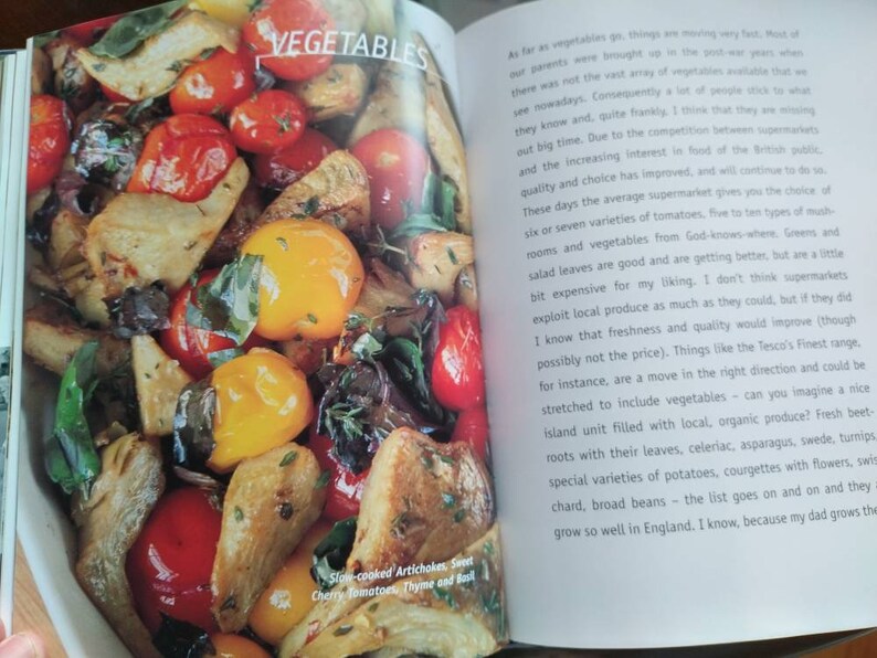 Puede incluir: Una imagen de primer plano de un taz&oacute;n de verduras asadas. Las verduras incluyen alcachofas, tomates cherry, pimientos amarillos y hierbas. El texto "Slow-cooked Artichokes, Sweet Cherry Tomatoes, Thyme and Basil" es visible en la esquina inferior izquierda de la imagen.