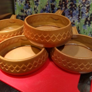 May include: Four brown ceramic bowls with a diamond pattern. The bowls are stacked on top of each other.