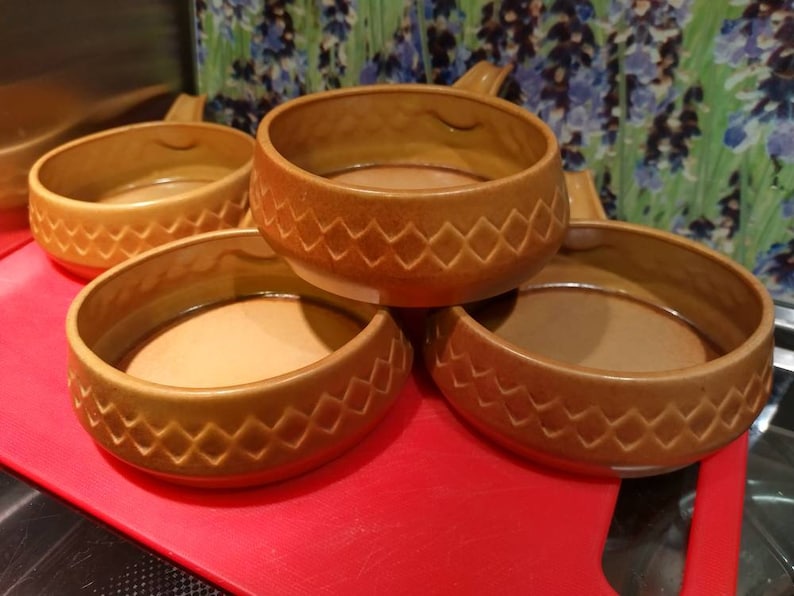 May include: Four brown ceramic bowls with a diamond pattern. The bowls are stacked on top of each other.