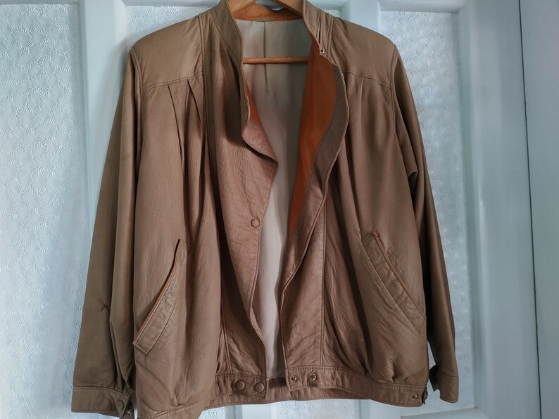 Puede incluir: Una chaqueta de cuero marr&oacute;n con cierre de cremallera y forro marr&oacute;n. La chaqueta tiene dos bolsillos en la parte delantera y un cierre de bot&oacute;n en el cuello.