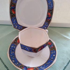 Puede incluir: Un juego de taza y platillo de t&eacute; blanco con un patr&oacute;n floral azul y dorado. La taza y el platillo tienen forma hexagonal.