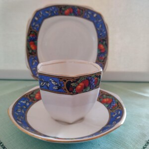 Puede incluir: Un juego de taza y platillo de t&eacute; blanco con un patr&oacute;n floral azul y dorado. La taza tiene una forma hexagonal y el platillo tiene un borde festoneado.