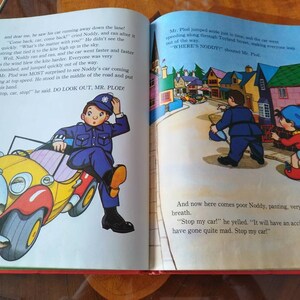 以下が含まれることがあります： 赤と黄色の玩具の車に青と白の凧が取り付けられています。車は警察官が乗っている状態で道を走っています。ページには「DO LOOK OUT, MR. PLOD!」という文字が書かれています。