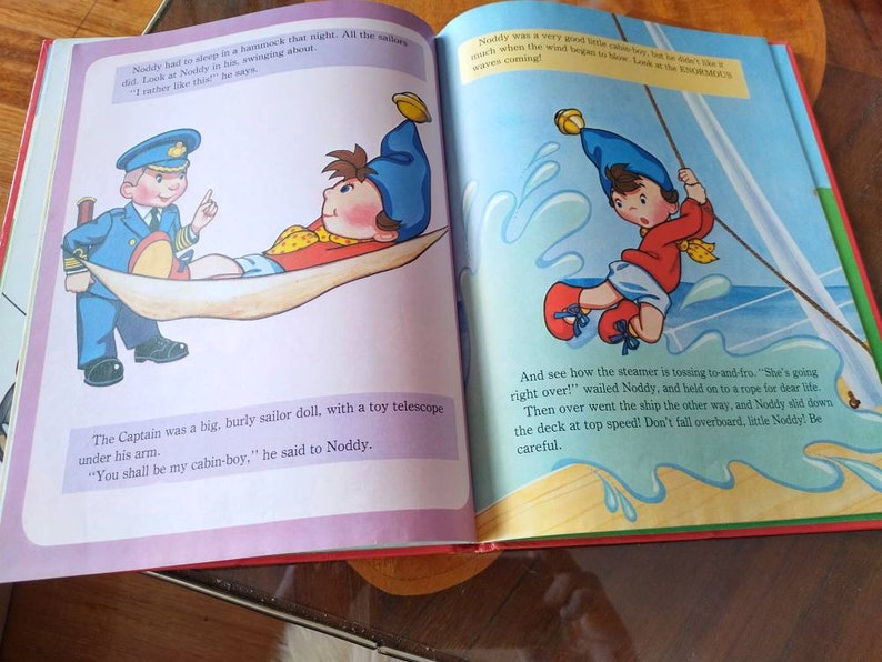 以下が含まれることがあります： 子供向けの本のイラストで、カートゥーンキャラクターのノッティが描かれています。ノッティは赤いシャツを着て、青い帽子をかぶっています。彼は船のロープを掴んでいます。テキストには、「そして、汽船が前後に揺れているのがわかります。 "ひっくり返るぞ！" ノッティは叫び、ロープにしがみついていました。そして、船は反対側に傾き、ノッティは甲板を高速で滑り落ちました！小さなノッティ、海に落ちないで！気を付けて！ 」と書いてあります。