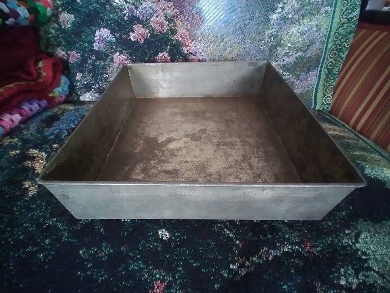 May include: A silver metal baking pan with a rectangular shape. The pan has a slightly worn surface.