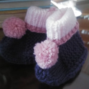 May include: A pair of knitted baby booties with pink pom-poms and a purple and white striped cuff.