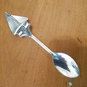 May include: Silver teaspoon with a sailboat design on the handle. The sailboat has the words "America's Cup 1987" on it.