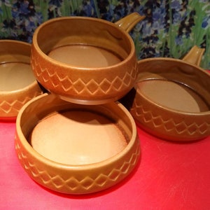 May include: Set of four brown ceramic bowls with handles. The bowls have a diamond pattern around the rim.
