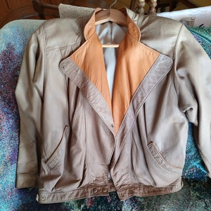 Puede incluir: Una chaqueta de cuero marr&oacute;n con forro de cuero beige. La chaqueta tiene cierre de cremallera y dos bolsillos.