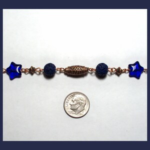 May include: A blue star charm bracelet with lava rock beads and a bronze spacer bead. The bracelet is about the size of a dime.