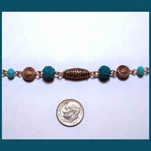 May include: A copper chain bracelet with turquoise and copper beads. The bracelet is about the size of a dime.