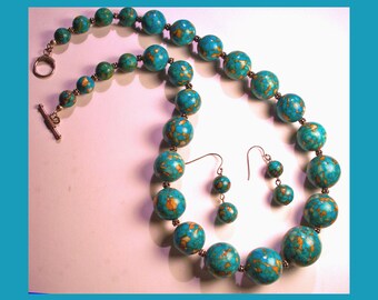 May include: A turquoise and gold necklace and earrings set with large round beads. The necklace has a silver toggle clasp.