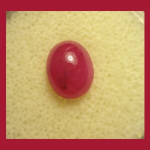 May include: A deep red oval-shaped gemstone with a smooth, polished surface.