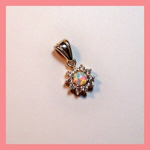 May include: A silver pendant with a white opal gemstone surrounded by a halo of clear cubic zirconia stones.