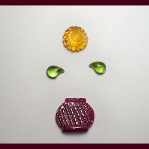 May include: Three carved gemstone cabochons: a yellow flower, a green teardrop, and a red basket.