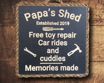 May include: Black wooden sign with rope trim, reading "Papa's Shed Established 2019 Free toy repair Car rides and cuddles Memories made". The sign features a screwdriver, wrench, and hammer.