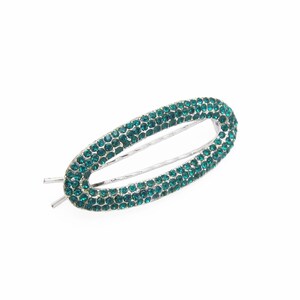 May include: A silver oval-shaped hair clip with a design of small, dark green rhinestones.