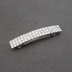 May include: Silver hair clip with a row of clear rhinestones.