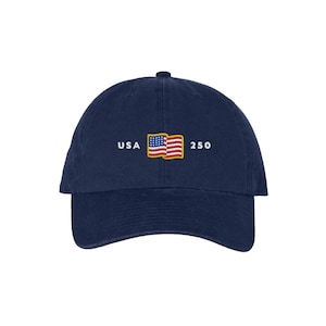 May include: Navy blue baseball cap with a curved brim. The cap features the embroidered text "USA 250" with an image of the American flag. The hat is a classic style, suitable for casual wear.